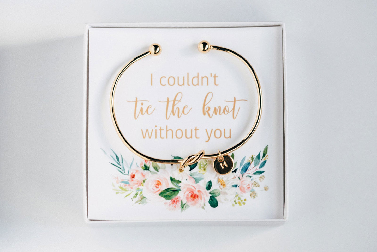 Golden personalized bridesmaid proposal bracelet with a initial charm in a box that says "I couldn't tie the knot without you"  