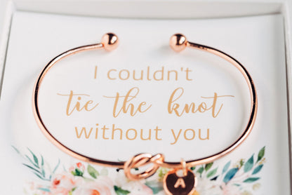 Golden personalized bridesmaid proposal bracelet with a initial charm in a box that says "I couldn't tie the knot without you"  