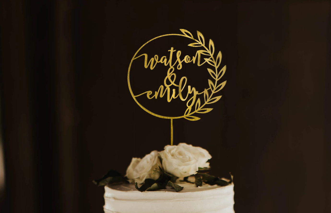 calligraphy personalized golden wreath style cake topper made of wood on top of the white simple wedding cake. 