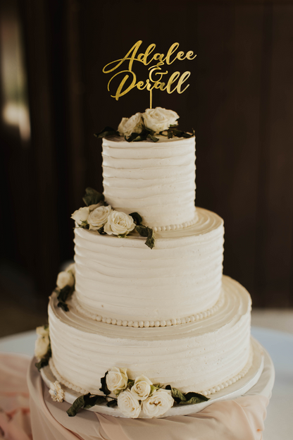 calligraphy personalized golden cake topper made of wood on top of the white simple wedding cake. 