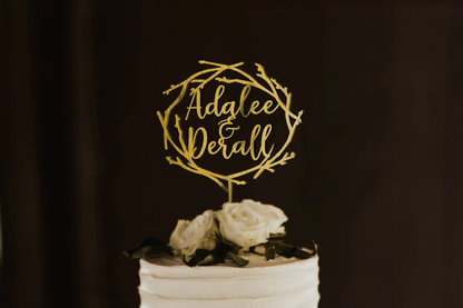 calligraphy personalized golden twig wreath style cake topper made of wood on top of the white simple wedding cake. 