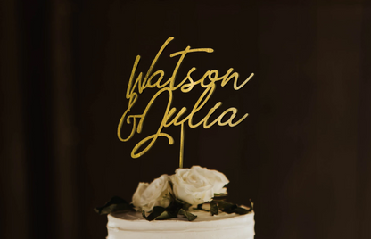 thin calligraphy personalized golden cake topper made of wood on top of the white simple wedding cake. 