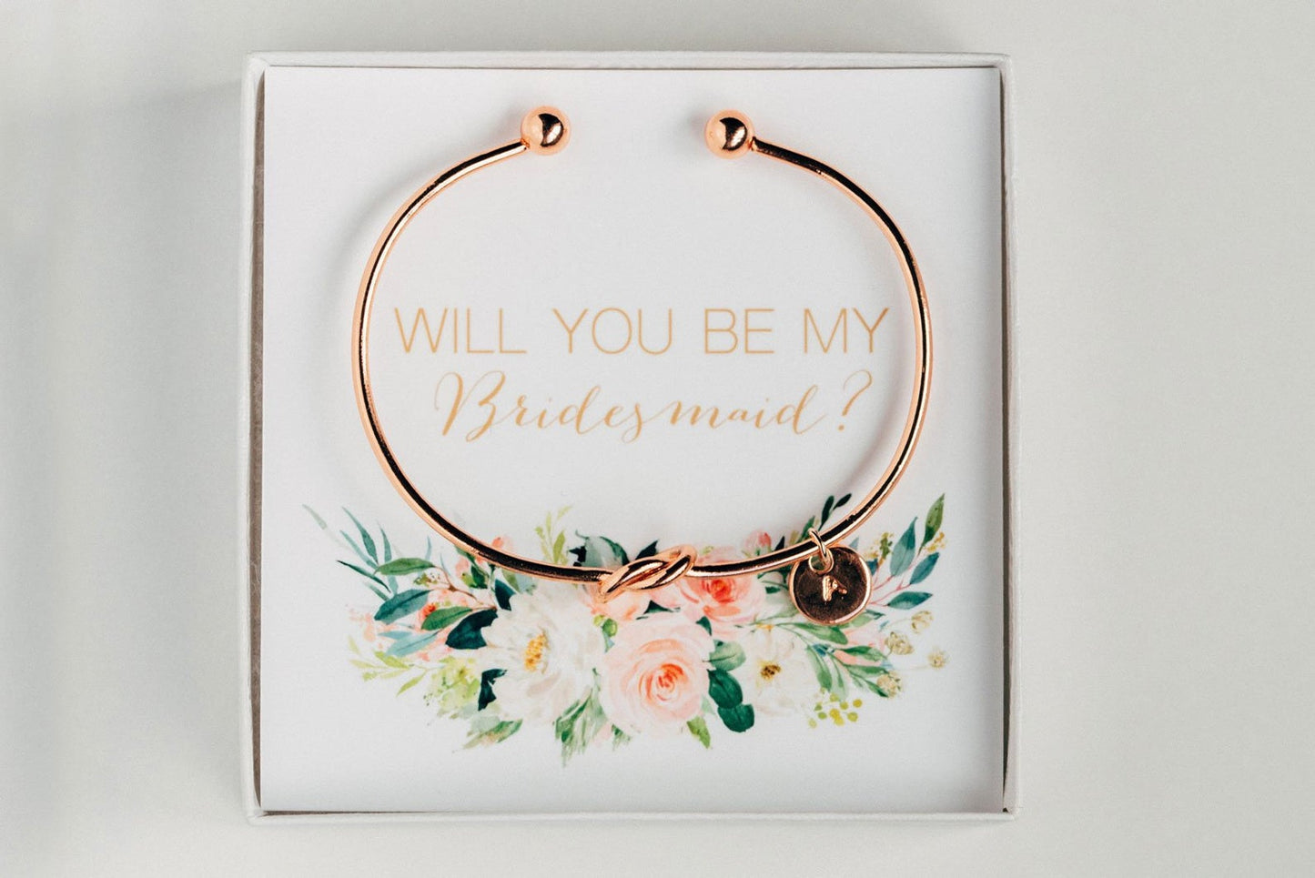 Golden personalized bridesmaid proposal bracelet with a initial charm in a box that says "Will you be my bridesmaid?"  