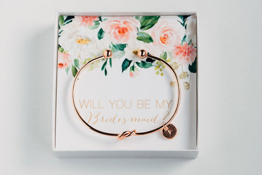 Golden personalized bridesmaid proposal bracelet with a initial charm in a box that says "Will you be my bridesmaid?"  